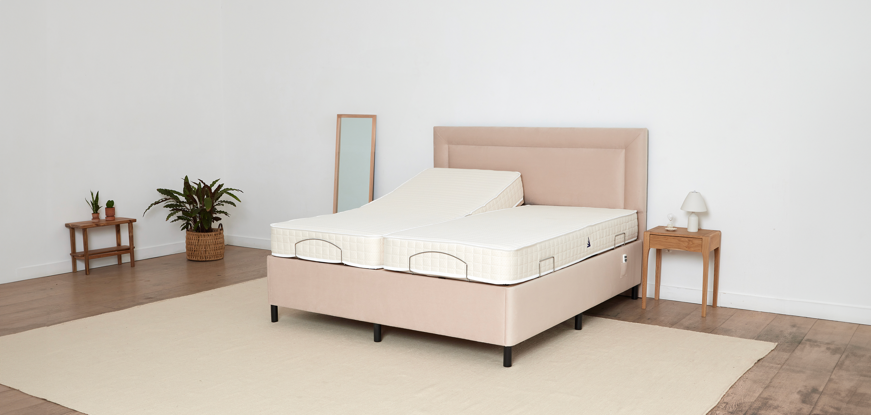 A 6 foot king size electric adjustable bed by the Natural Sleep Company in colour beige in a minimalist modern white bedroom with a wooden floor and indoor plants
